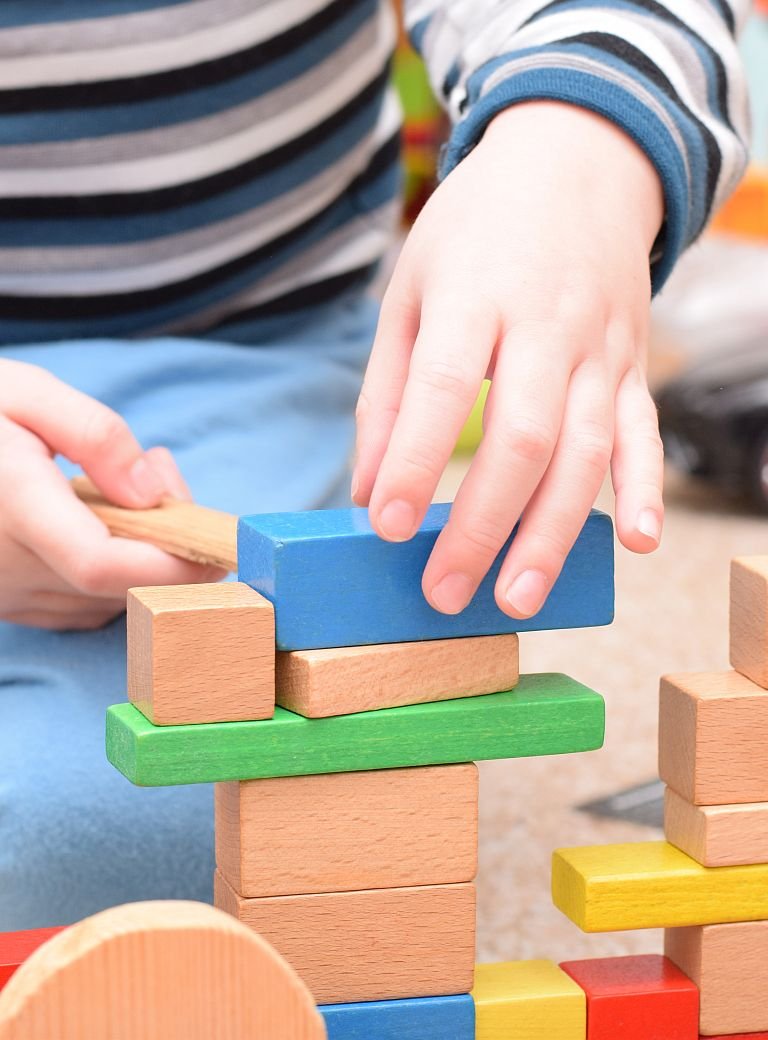 Kinderhände spielen mit bunten Holzbausteinen 