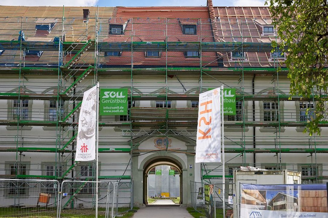 Eingang zum Arkadenhof des Klosters Benedikbeuern mit Gerüsten und je einer Fahne der Salesianer Don Boscos und der KSH